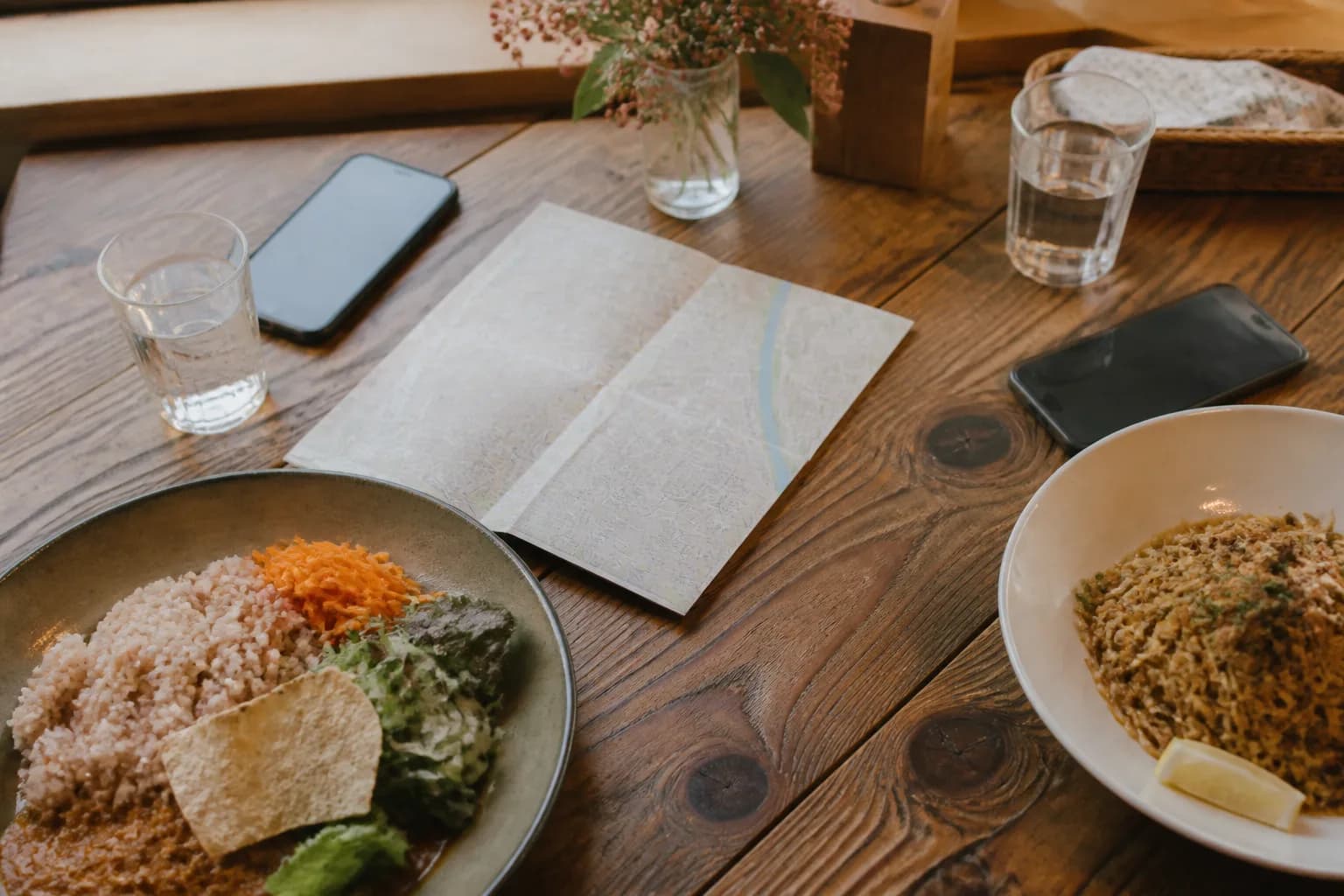 カフェのテーブルに並んだ料理と、ふたり分のスマートフォン